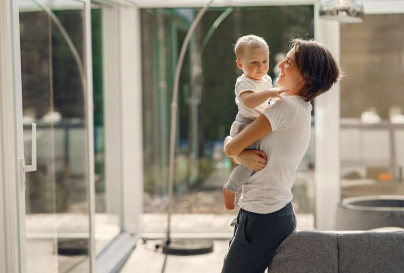 mamma felice con il suo bambino in casa piena di luce